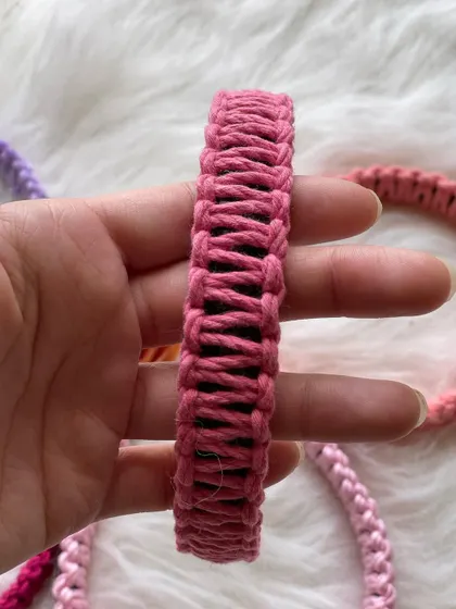 A close-up of a beautiful rose-pink macrame hairband. The detail in the weaving shows the care I put into making each piece both pretty and practical.