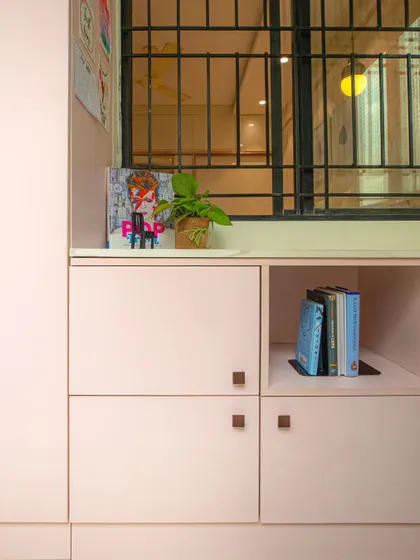 The study nook includes cabinets in a soft pink suede-finish laminate with elegant rose gold handles, offering plenty of storage for books and school supplies.