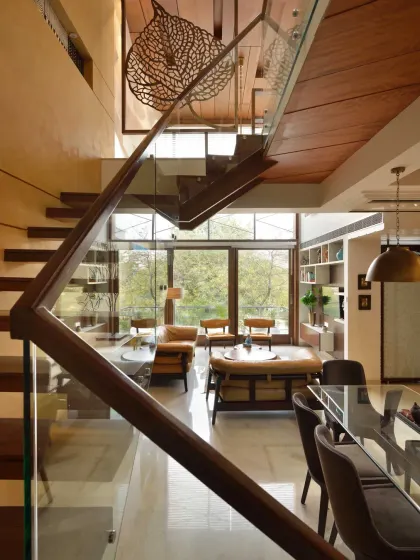 In the Kavyam Residence, a double-height glass opening in the dining area brings in abundant natural light and offers a beautiful view of a tree outside, blurring the line between indoors and out.