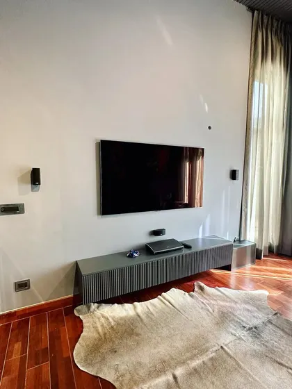The TV wall in the lounge is kept simple with a floating console to maintain a clean, uncluttered look. The focus remains on the art and the comfortable seating.