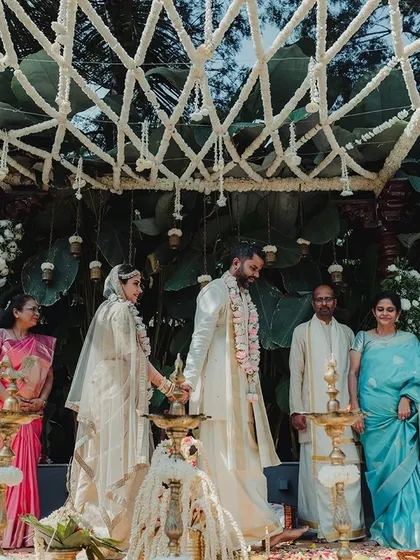 A beautiful moment from a Christian wedding ceremony, with the couple lighting the lamp under a canopy of white jasmine, symbolizing a bright new beginning.