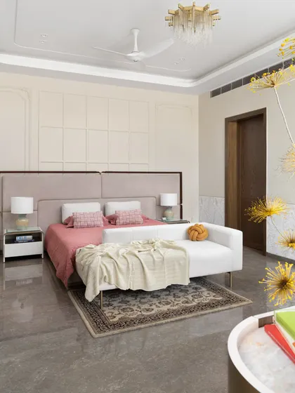 A serene bedroom in the "Ideal Home" project, featuring a soft, neutral palette with pops of pink. The elegant wall paneling and contemporary chandelier add a touch of classic luxury.