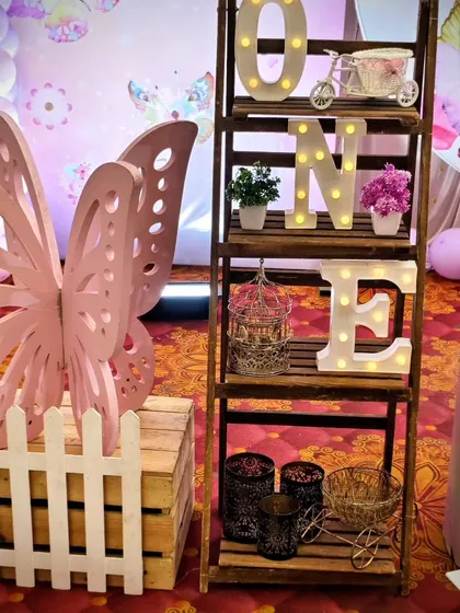 A close-up of a decorative ladder and butterfly wing prop from a pink-themed party.