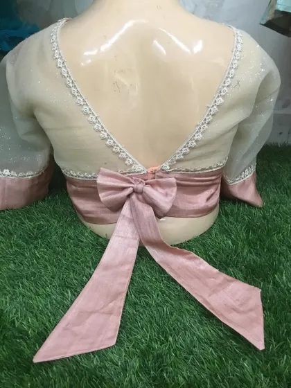 The back of this elegant blouse features sheer net sleeves and a large satin bow.