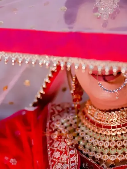 A playful and shy bridal portrait. The bride peeks out from under her veil with a smile, a charming and candid moment from her wedding day.