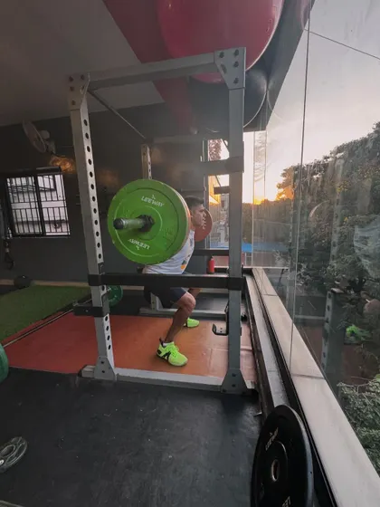 A client executes a heavy back squat inside a power rack, a safe and effective way to build serious lower body strength.