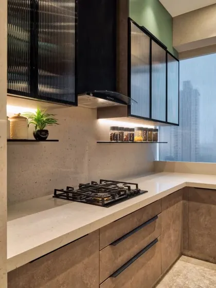 This design combines earthy brown cabinets with a textured countertop and fluted glass on the upper cabinets. The open shelves and under-cabinet lighting create a warm, inviting, and modern kitchen.