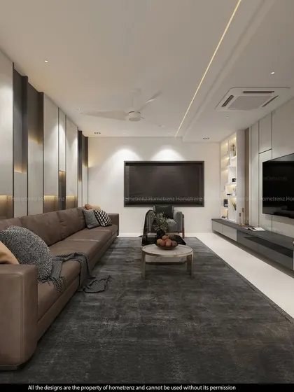 A spacious and luxurious living room with a large L-shaped leather sofa. The TV is mounted on a wall with alternating panels of marble finish and dark texture, creating a grand and impressive feature.