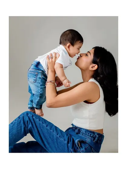 A mother lifting her baby up for a kiss, a classic and joyful pose for a milestone shoot.