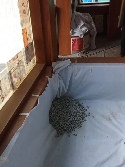 The foundational layers of an indoor garden. Gravel is added over a waterproof liner for drainage before the soil is put in, a crucial step for a healthy built-in planter.