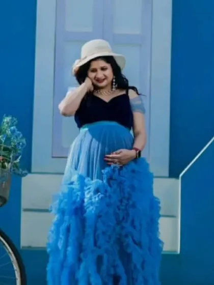 Our blue ruffled gown features a velvet bodice and a full tulle skirt, offering a unique mix of textures. It's a wonderful choice for a themed maternity shoot, shown here with a charming bicycle prop.