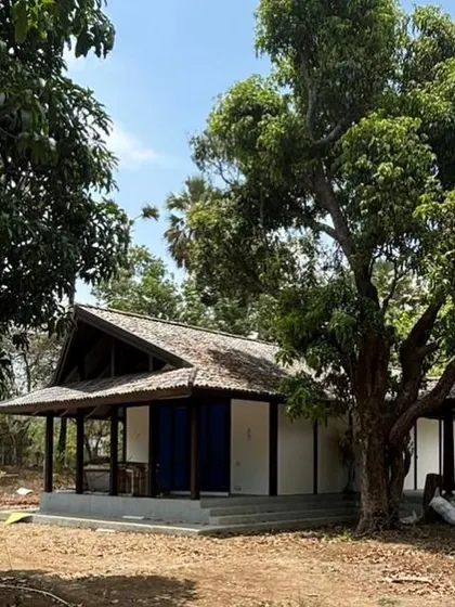 A contemporary pitched-roof home in Alibaug, designed to sit lightly on the land. The structure uses glue-laminated timber and large overhangs to respond to the local climate and blend with the rural setting.