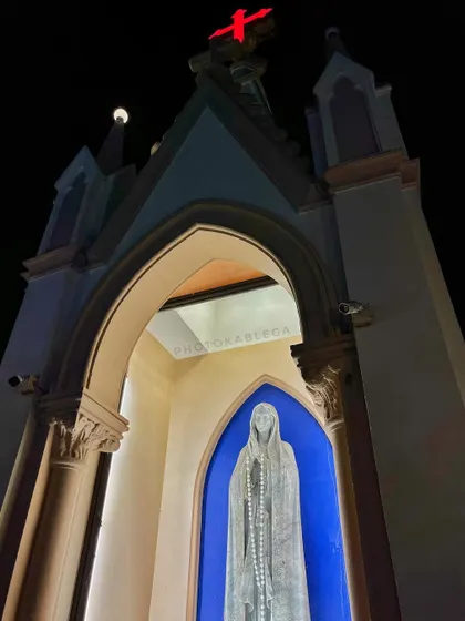 A close-up, upward-looking view of the entrance archway of Mount Mary Church, with a statue of Mary set against a striking blue background.