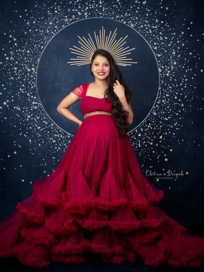 Celestial and radiant. This stunning magenta gown with a tiered skirt, paired with a celestial halo prop, creates a truly magical and artistic pregnancy portrait.