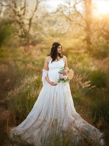 A portrait of the expectant mother looking serene and beautiful in a field at sunset. The light catches her hair and dress perfectly, creating a magical, dreamy effect.