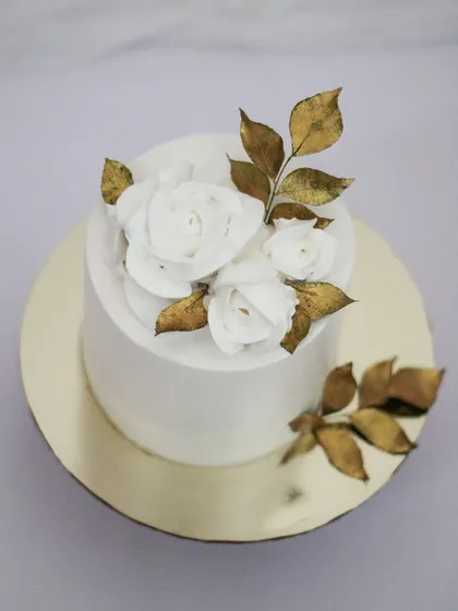 A top-down view of this elegant white and gold cake. You can see the delicate texture of the white chocolate roses and the shimmer of the gold leaves. Most often, less is more.