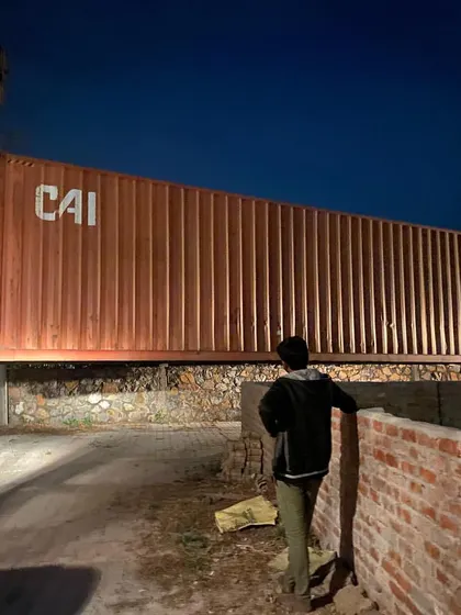 The container is precisely lowered into place, marking the foundational moment of the structure. This process requires careful planning and execution.