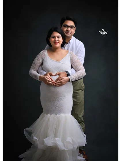 A lovely couple's pose where they create a heart shape with their hands on the baby bump. This shot beautifully symbolizes their shared love for their coming child.