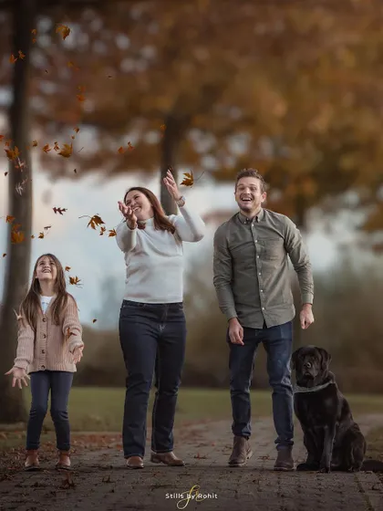 The whole family joins in on the autumn fun! A candid shot of them playing with leaves, with their stoic black lab looking on, perfectly captures the joyful chaos of family life.