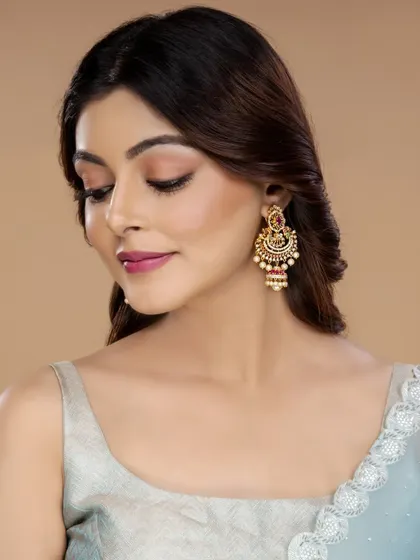 A close-up on a pair of traditional gold jhumka-style earrings with red stones, perfect for highlighting specific items in a collection.