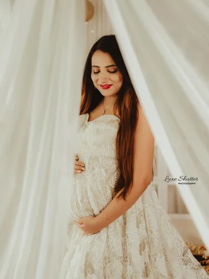 Using sheer white curtains creates a soft, ethereal filter for the light, adding a dreamy and romantic quality to this beautiful maternity portrait.