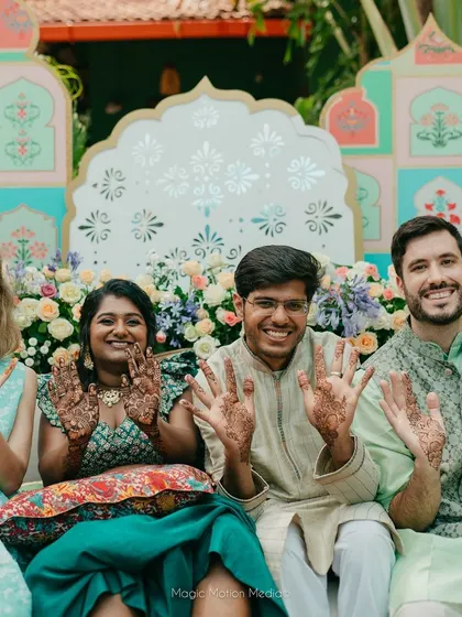 The couple poses with their friends, all showing off their henna designs, creating a fun and memorable group photo.