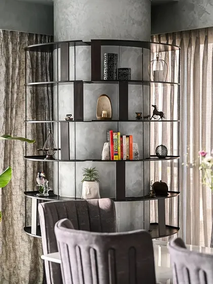This bespoke circular shelving unit was our solution for a large column in the dining area. It serves as both a functional display for decor and a striking piece of art, seamlessly integrating the structural element into the room's design.