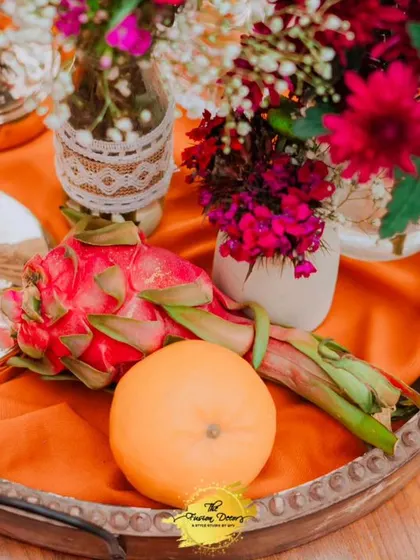 A close-up of a centerpiece detail, where fresh dragon fruit and an orange are artfully arranged with flowers, showing my commitment to unique and natural decor elements.