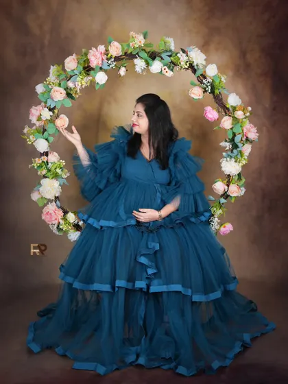 Another beautiful take on our floral hoop setup. The mom-to-be looks serene in a tiered blue gown, creating a lovely contrast with the soft colors of the flowers.