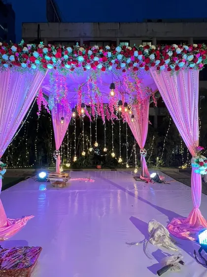 This mandap, illuminated with soft purple lighting and hanging bulbs, creates a magical ambiance for an evening wedding ceremony. It's both elegant and breathtaking.
