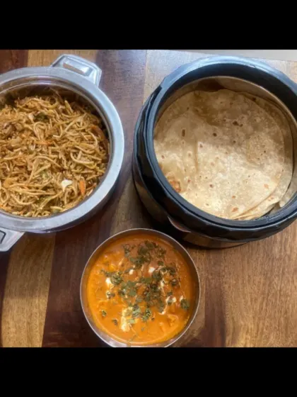 Egg noodles, chapathi and paneer butter masala are arranged together in our home-cooked dinner spread.