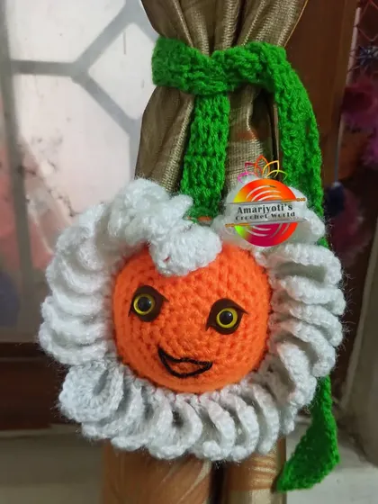 This is a fun, character-inspired curtain tie-back. It features a smiling orange face surrounded by fluffy white petals, bringing a cartoonish charm to your decor.