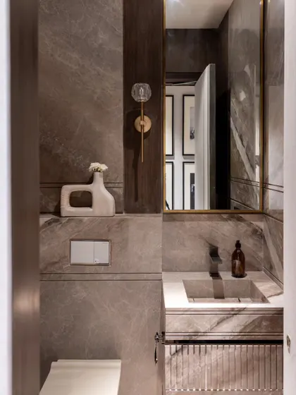 A powder room in the Skyward Residence, clad in warm grey marble. The fluted vanity and minimalist fixtures create a space that is sophisticated and serene.