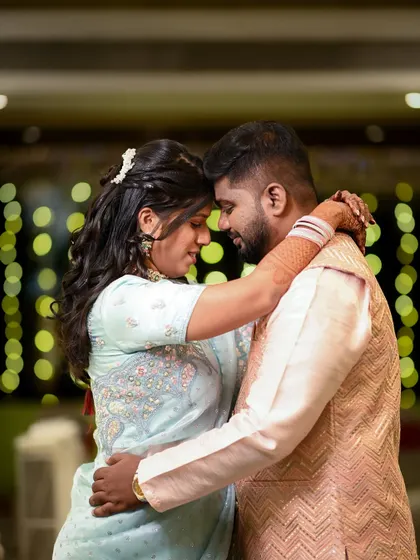 A deeply romantic portrait of the couple in a close embrace, foreheads touching. The warm, ambient lighting enhances the intimacy of the moment.