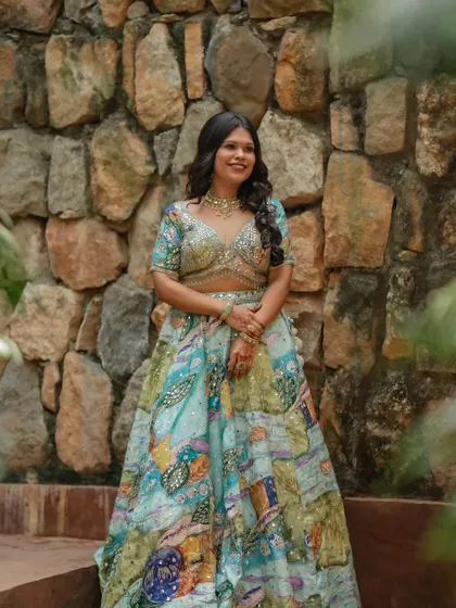 Rachana at her welcome event, looking beautiful against a rustic stone wall.