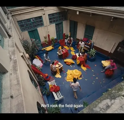 An overhead shot from a commercial I styled for the East Bengal Football Club. The scene is filled with vibrant red and yellow fabrics, creating a visually rich and energetic atmosphere.