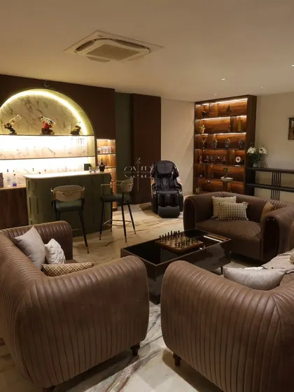 This wide view of the Harmony House bar area shows the cozy, customized sofas arranged for conversation, with the backlit bar display as a stunning backdrop.