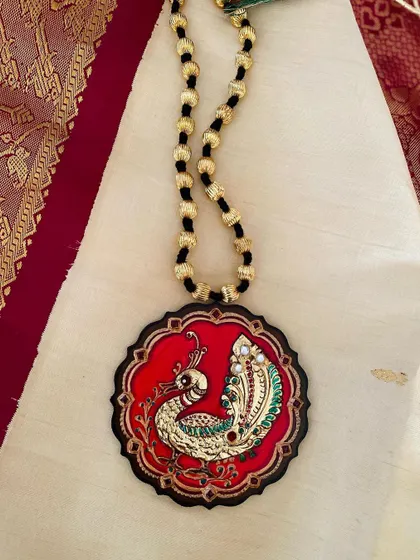 This photo captures the red peacock pendant against a cream silk saree, illustrating its versatility and elegance.