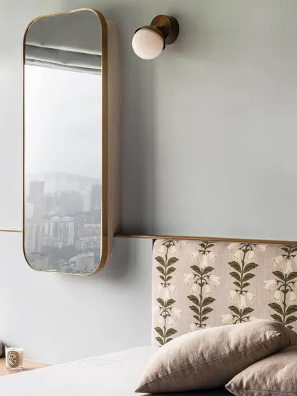 The master bedroom in Apartment 3201, where a cool blue wall color creates a serene and calming atmosphere. The custom headboard with floral fabric and a minimalist mirror add layers of texture and sophistication.