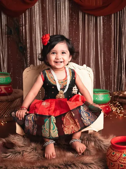 This little one's smile is so infectious. The rich colors and textures of the traditional Indian dress and props create a vibrant and culturally rich portrait.
