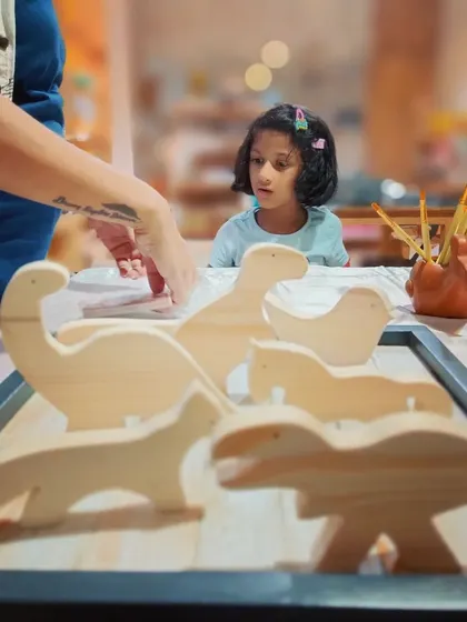 A young creator carefully inspects the wooden animal shapes from our DIY kit. We love sparking that initial moment of curiosity before the painting begins.