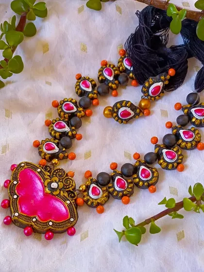 The butterfly-pendant necklace in a vibrant pink and orange.