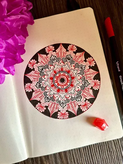 A pop of red brings a different energy to this otherwise black and white piece. The selective use of color draws the eye to the center, highlighting the core of the intricate mandala design.