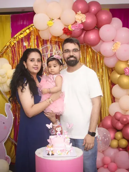 A family stands by the cake table during a pink elephant-themed birthday party. Our photographers capture both posed family portraits and the overall party setup.