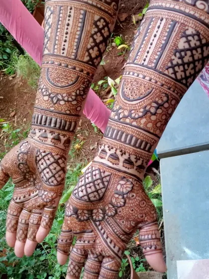 This design shows the beauty of a fully developed henna stain. The intricate patterns covering the hands and extending up the arms have turned into a deep, rich color, ready for the wedding day.