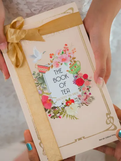 A shot of hands gifting "The Book of Tea," a beautifully designed tea box, perfect for special occasions.