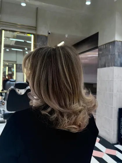 The final result of a cool blonde balayage, styled with soft curls. This look is perfect for anyone wanting a sophisticated and modern hair color.