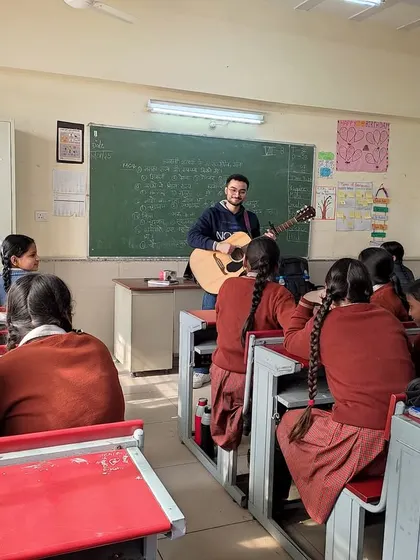 A fellow plays guitar for an attentive class. These sessions are often the highlight of a student's week, providing a creative outlet and a break from traditional academic lessons.