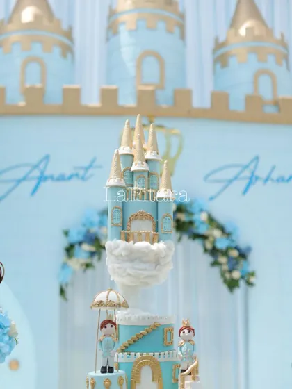 A close-up of an incredibly detailed castle cake, designed to perfectly match the royal theme. The cake itself is a work of art, featuring turrets, clouds, and miniature prince figurines.