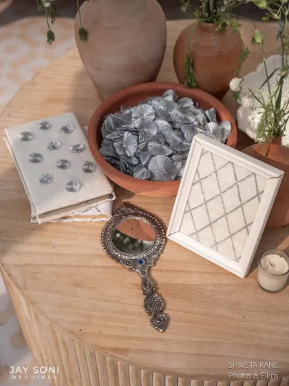A collection of curated objects for the ivory wedding, including a traditional silver hand-mirror and other trinkets, adding a personal and vintage touch.